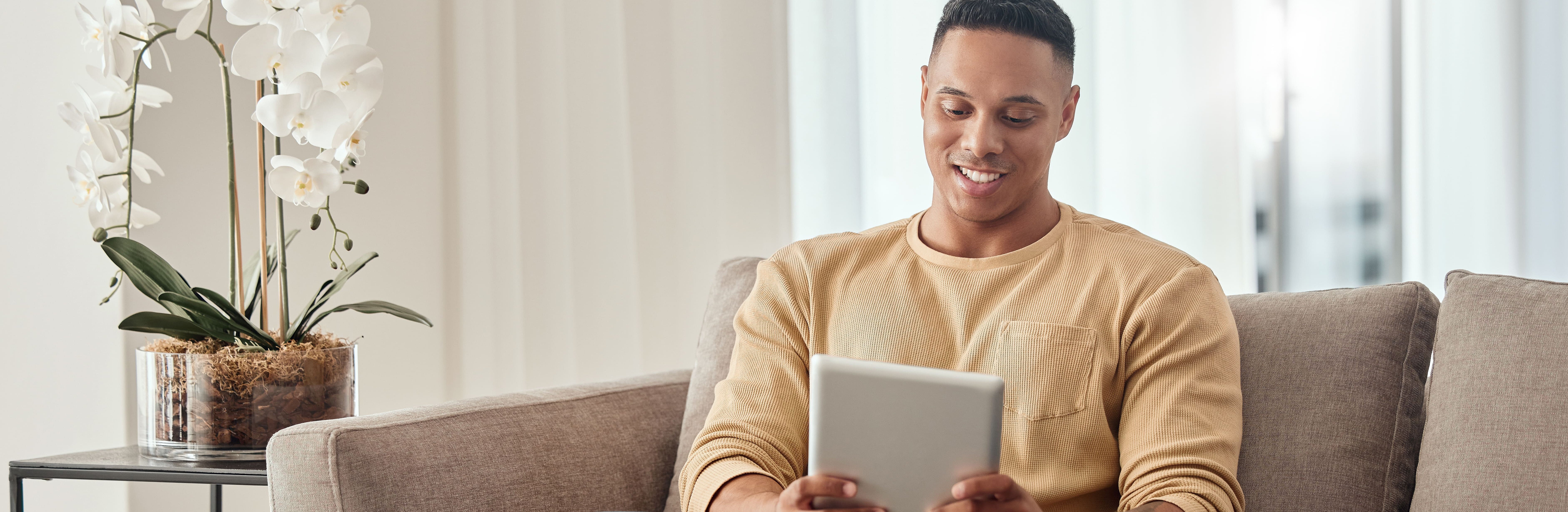 Junger Mann auf Sofa mit Tablet-PC.