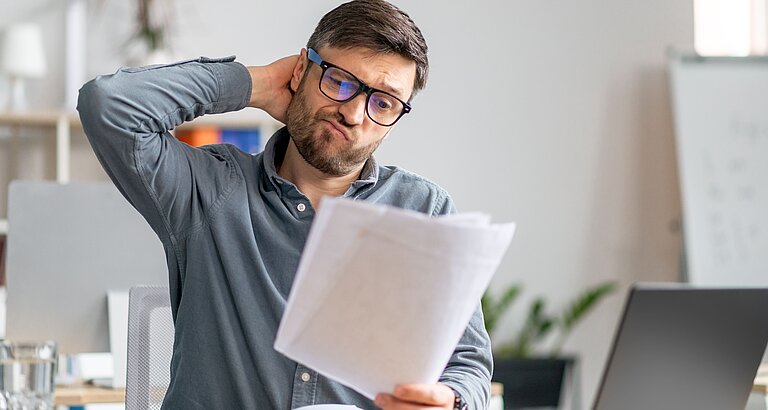 Mann sitzt grübelnd über Rechnung