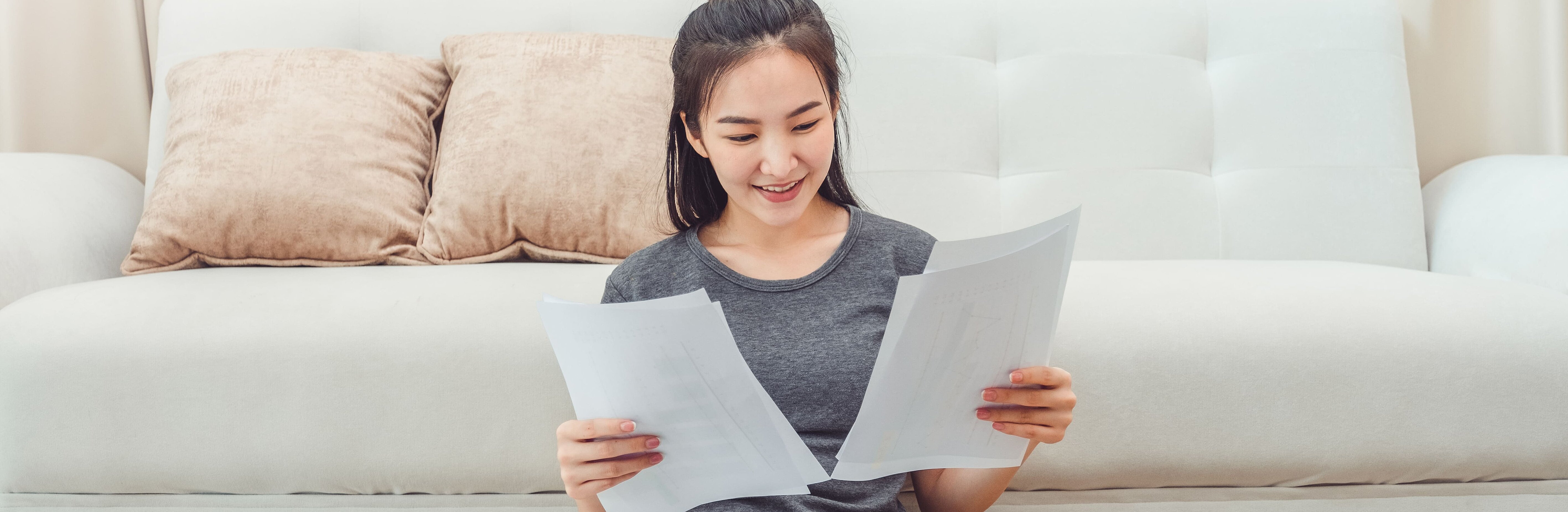 Junge Frau sitzt im Wohnzimmer und überprüft Rechnungen