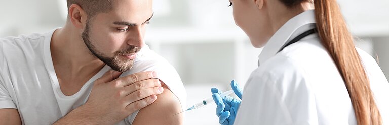 Ärztin setzt Mann eine Spritze in den Oberarm