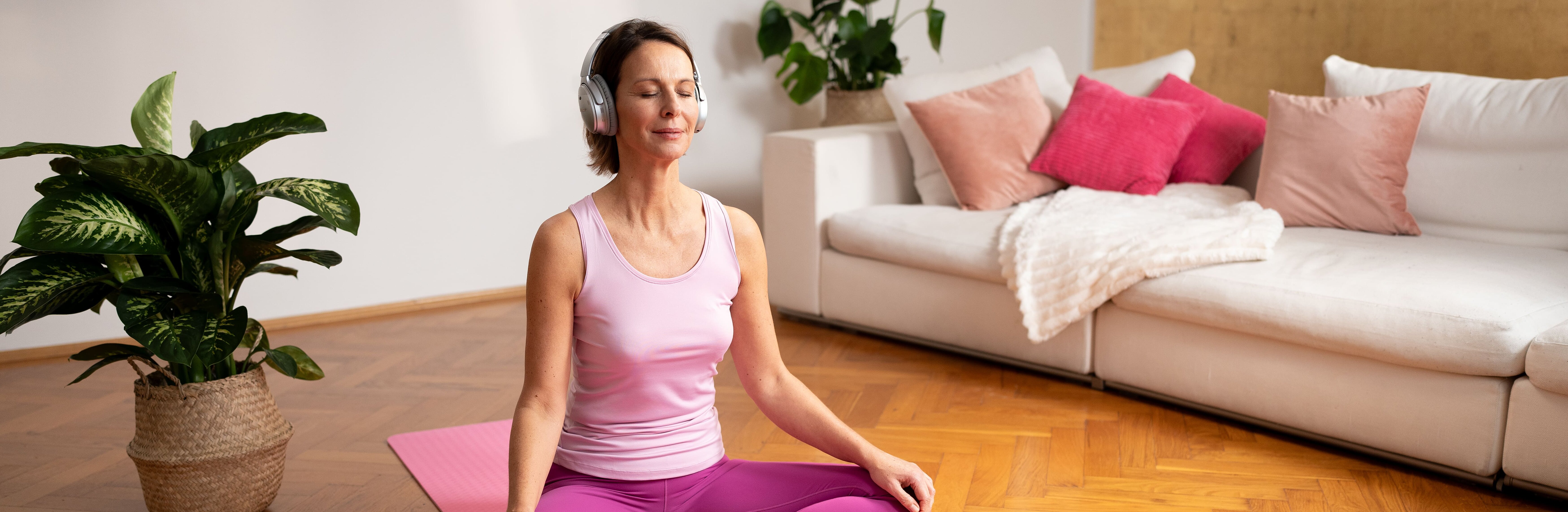 Frau sitzt auf Yogamatte und macht Entspannungsübung