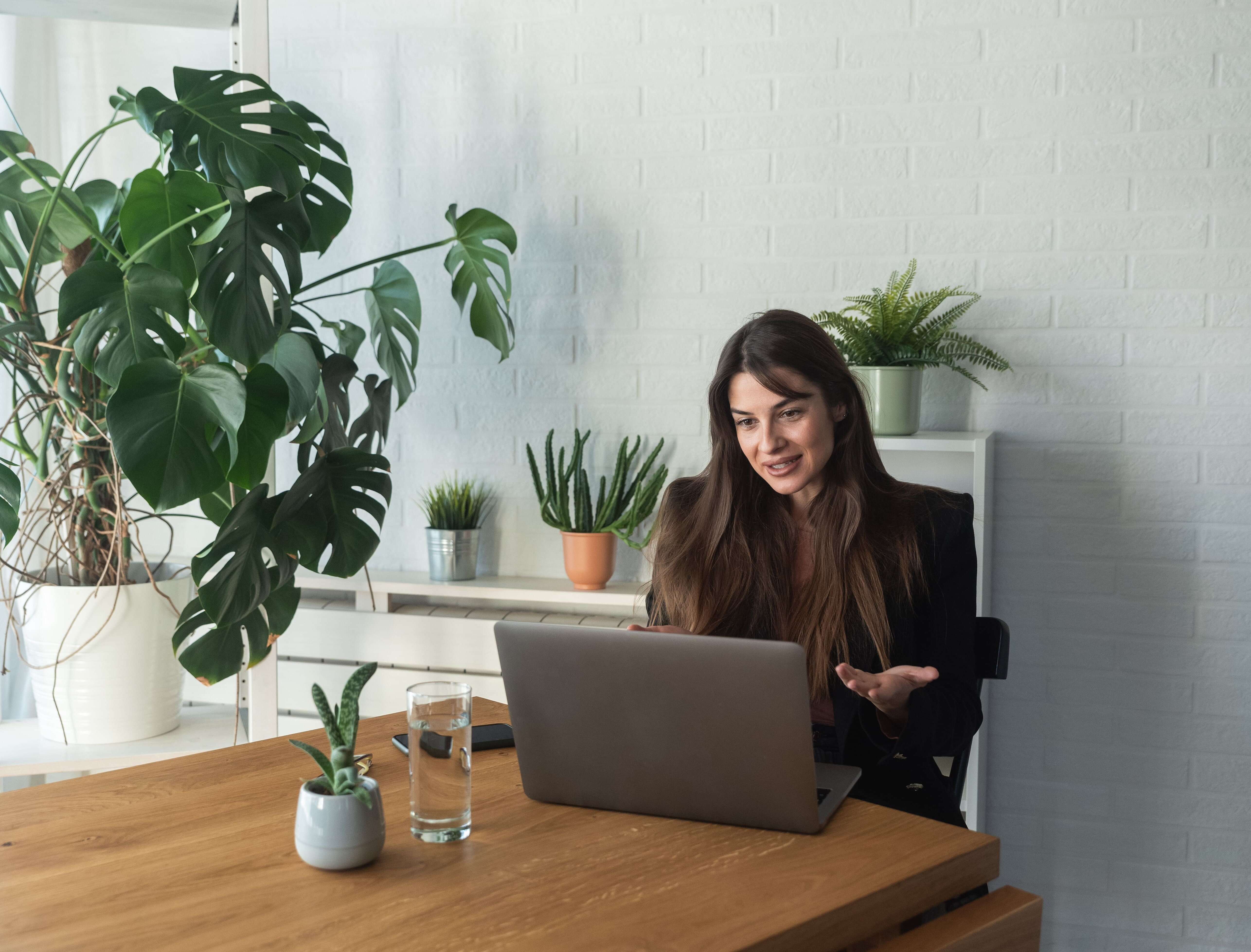 Frau sitzt am Esstisch und spricht über Laptop