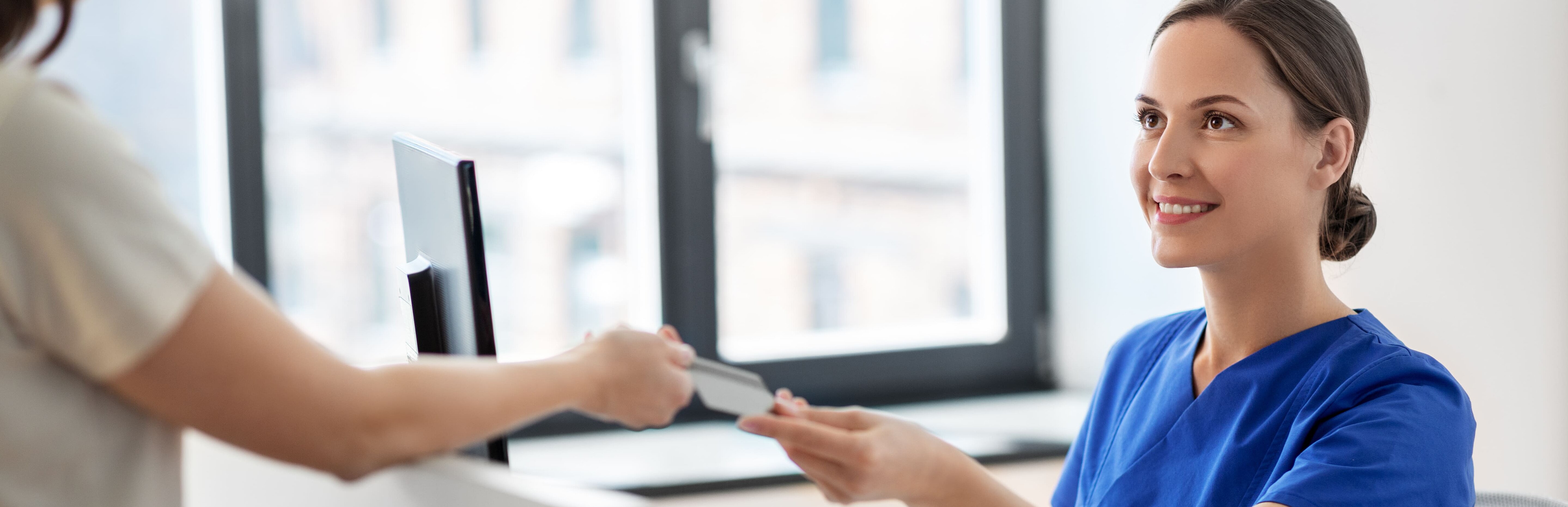 Patient überreicht Arzthelferin seine Gesundheitskarte