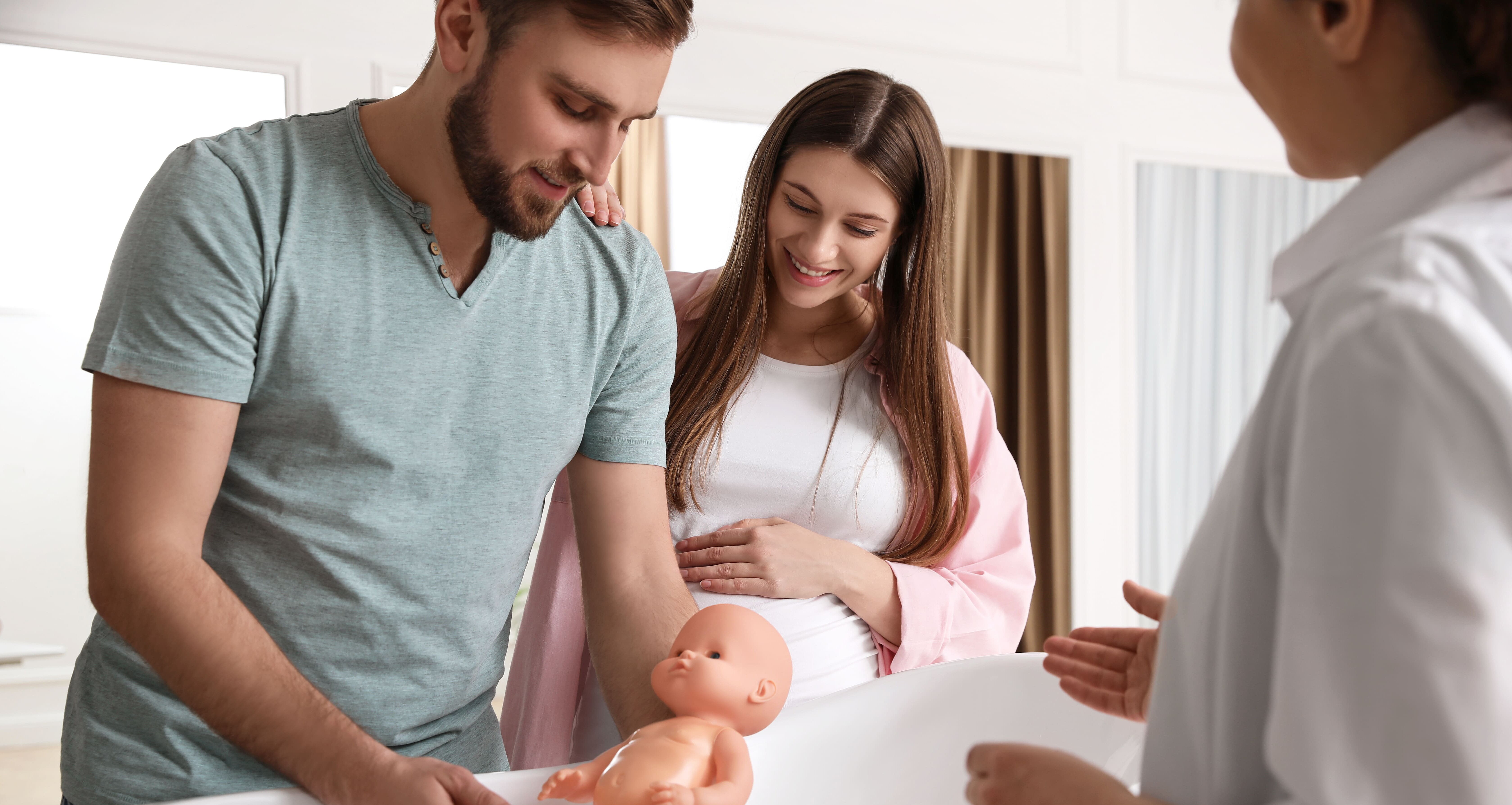 Werdende Eltern üben das Baden Ihres Baby anhand einer Puppe