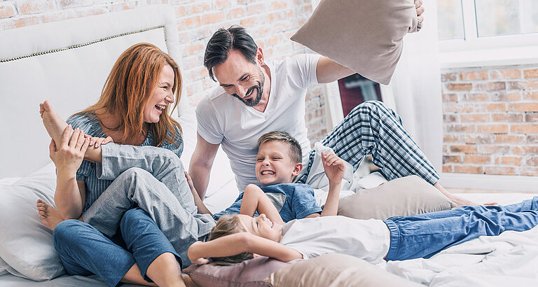 Familie tobt im Bett