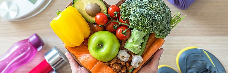 Schale mit gesundem Obst und Gemüse, Sportausrüstung.