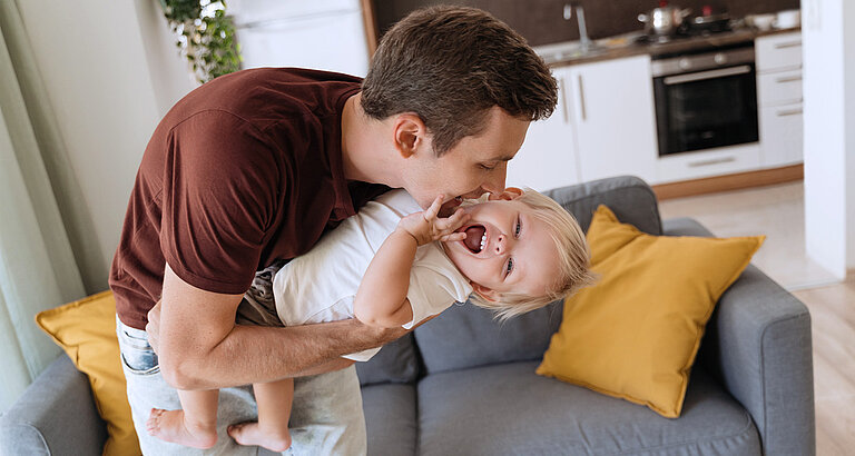Vater tobt mit kleinem Kind auf dem Arm