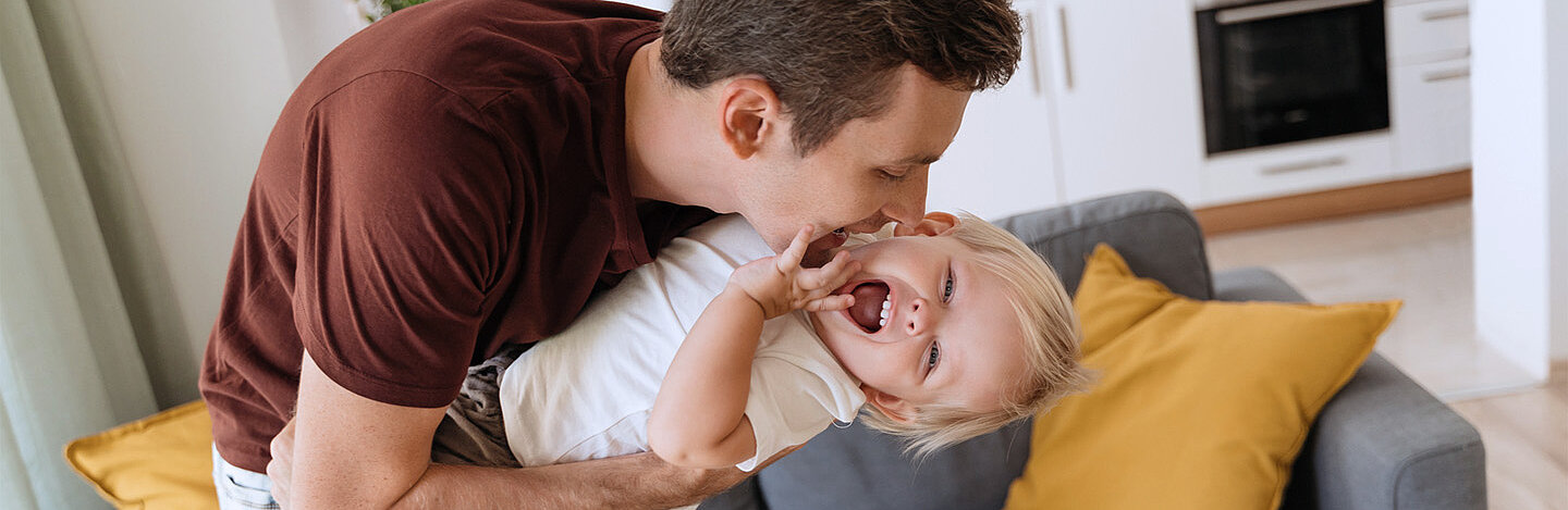 Vater tobt mit kleinem Kind auf dem Arm