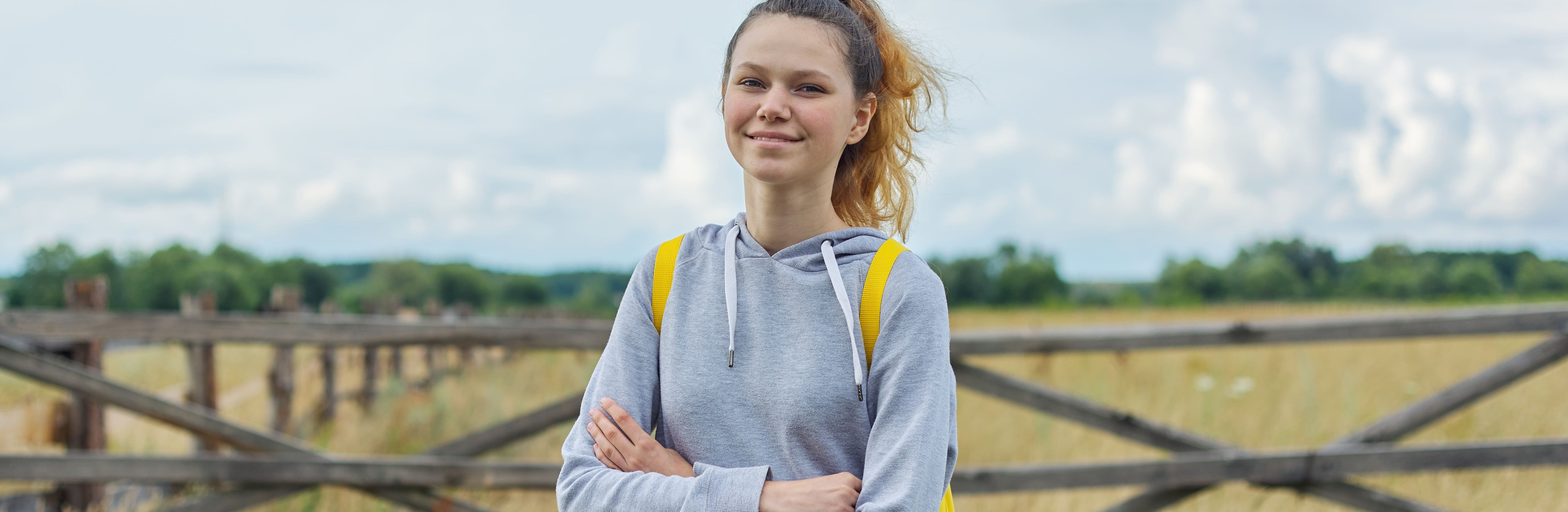 Teenager-Mädchen mit verschränkten Armen lächelt in die Kamera