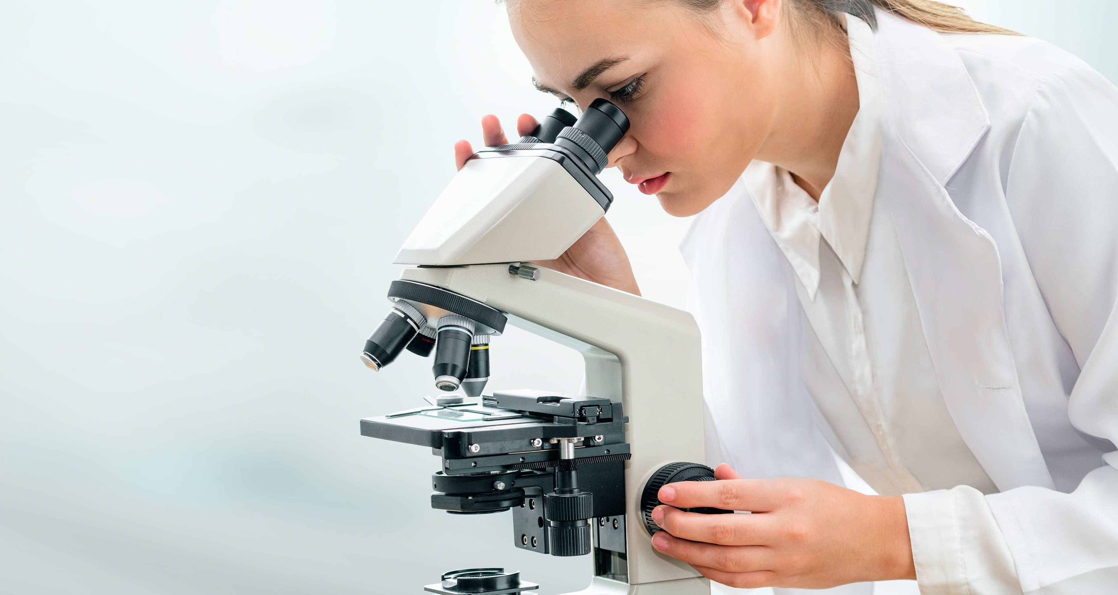 Frau guckt durch ein Mikroskop