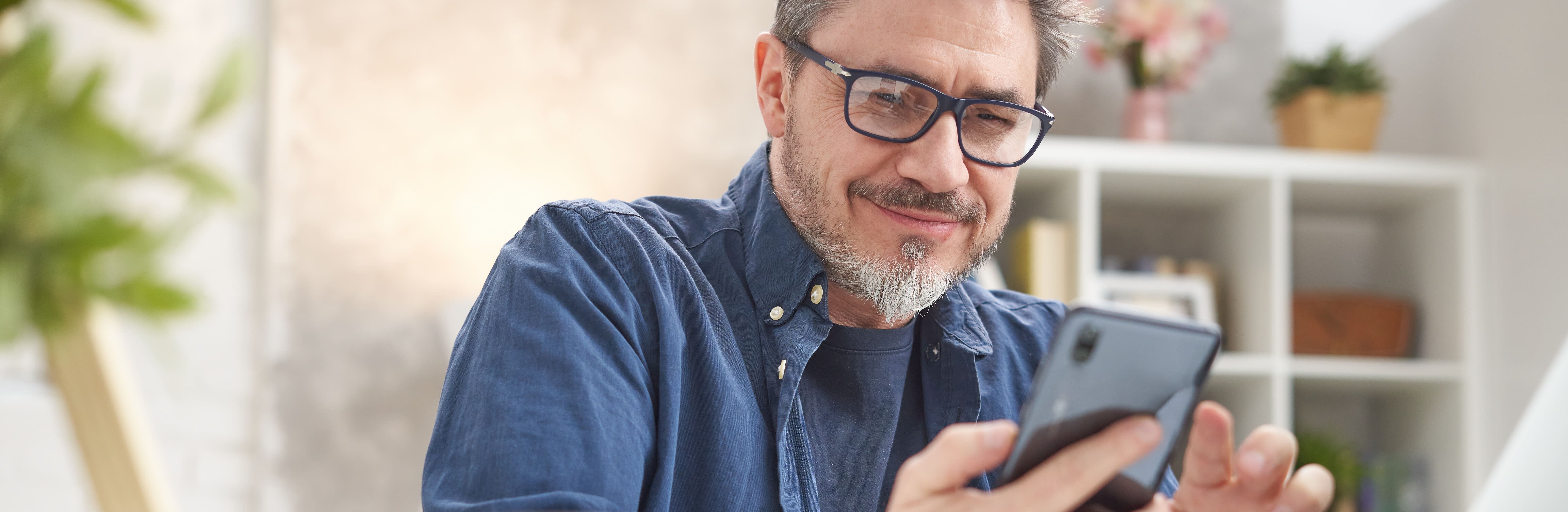 Mann schaut entspannt in sein Smartphone