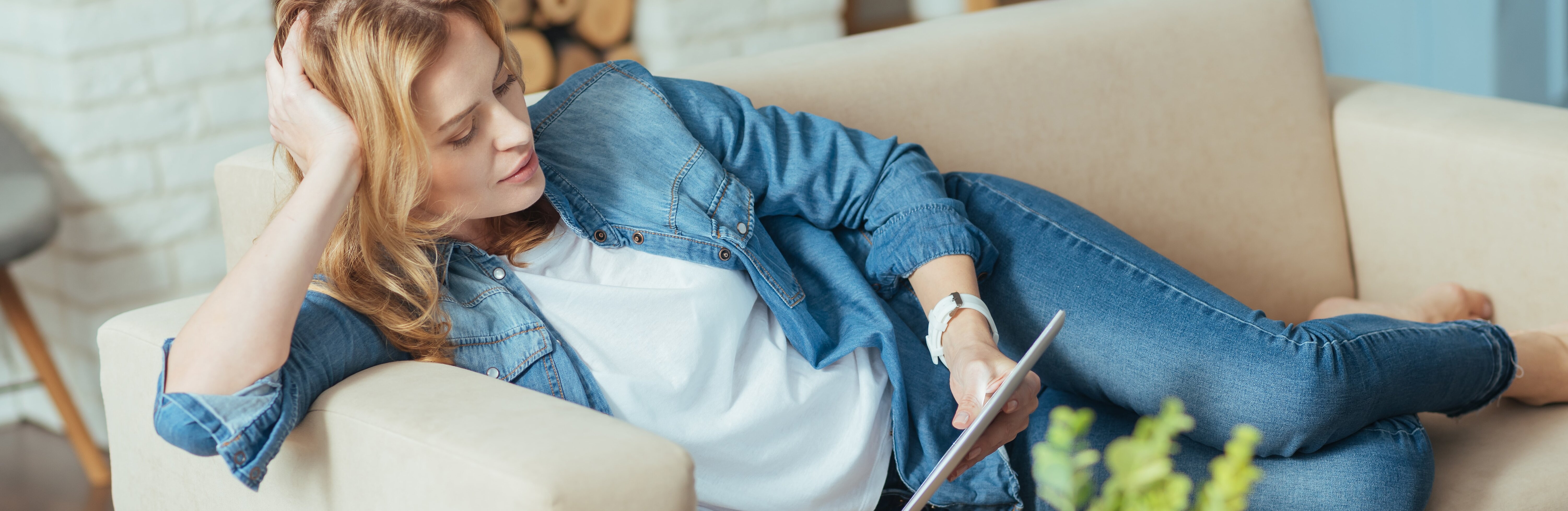 Frau sitzt auf dem Sofa mit einem Tablet in der Hand