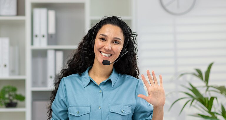Frau telefoniert mit Headset und lächelt freundlich