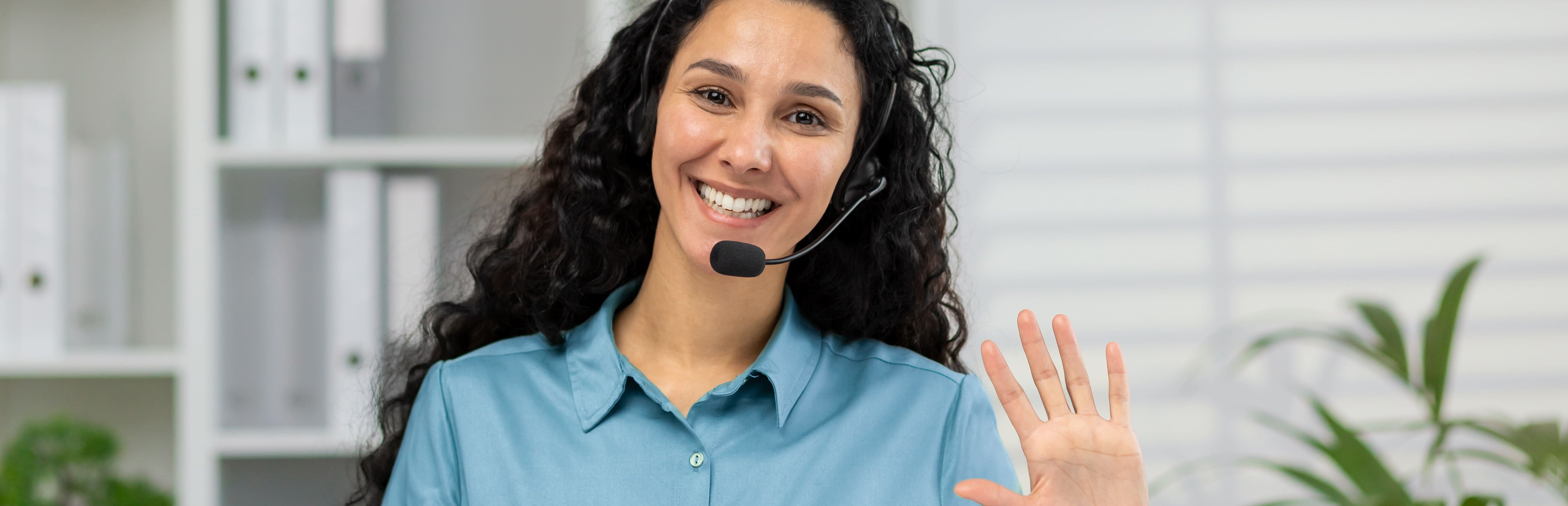 Junge freundliche Frau spricht in ein Telefon-Headset.